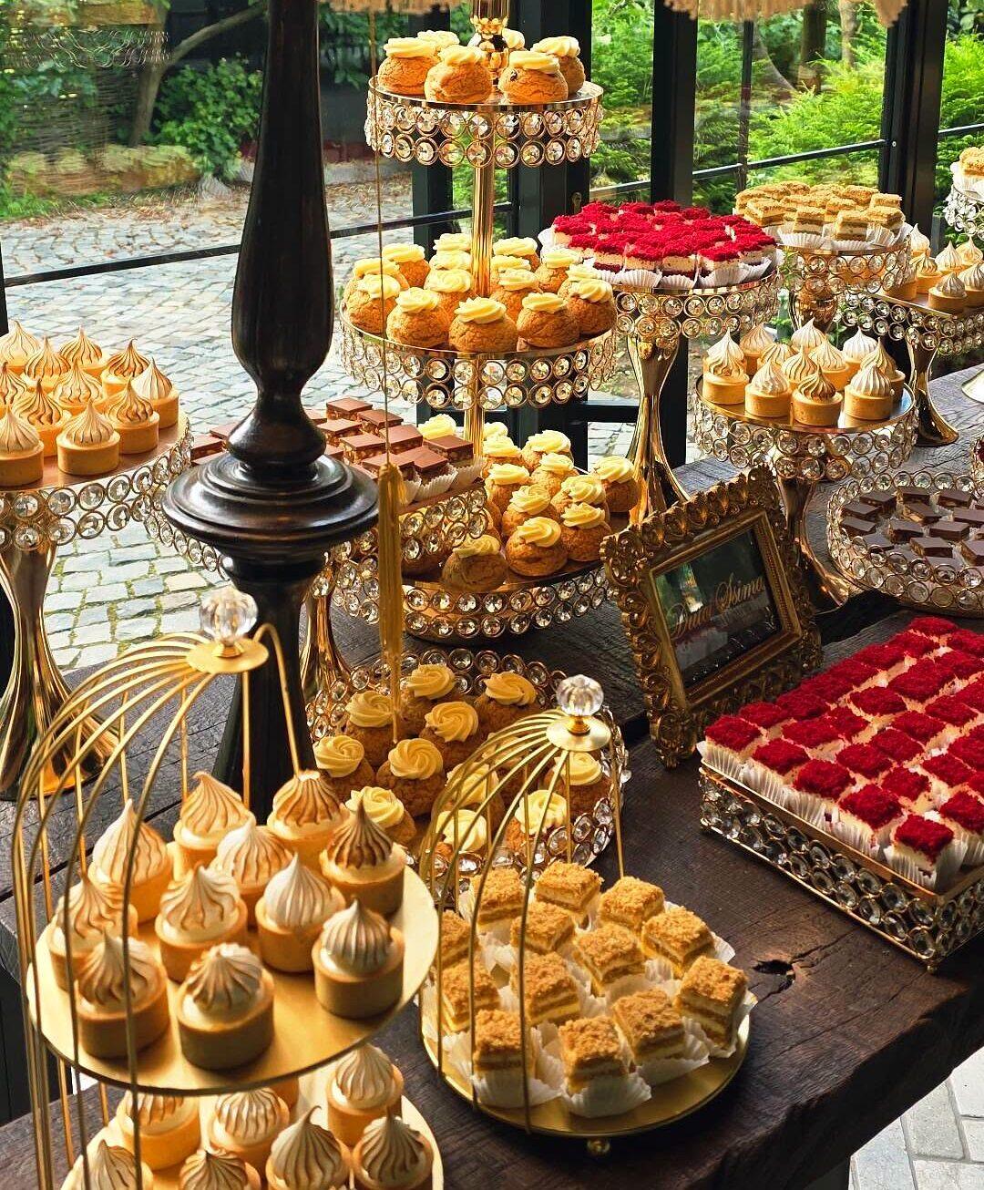 Candy bar cu choux, bezele și monoporții roșii, aranjate pe suporturi aurii